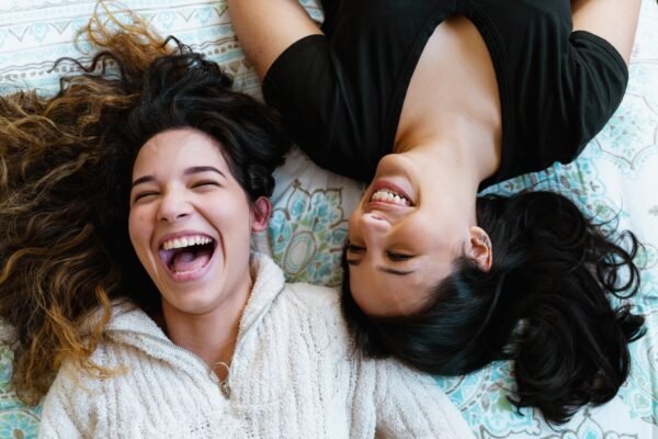 two women laying on blanket looking up and laughing